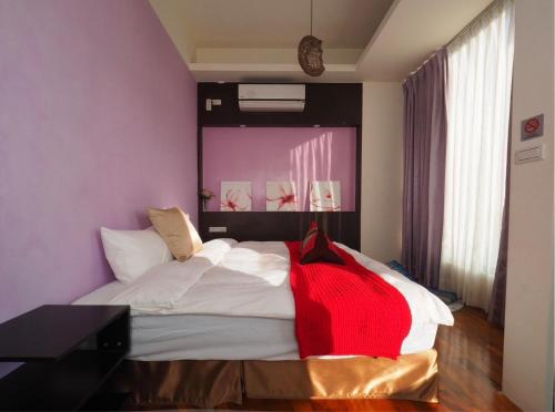 a bedroom with a bed with a red blanket on it at 198紅帽民宿l市區l2025冷氣全面換新 in Magong