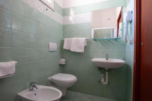 a green bathroom with a toilet and a sink at Hotel De La Ville in Rimini