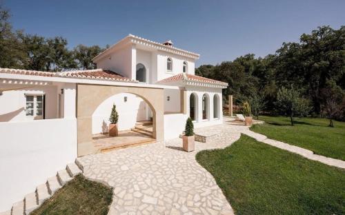 duży biały dom z łukiem na podwórku w obiekcie Traumhaftes Ferienhaus mit privatem Pool und Tennisplatz im Herzen Andalusiens w mieście Alhama de Granada