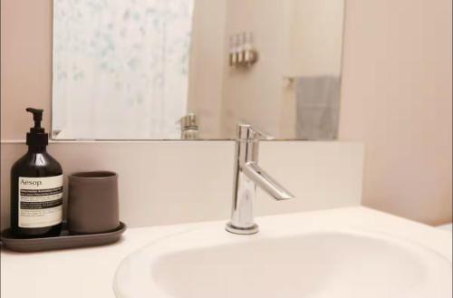 a bathroom sink with a bottle of soap and a mirror at Cozy 2BR Private Basement Suite, Free Parking, WiFi, 1 Hr to Banff, 20 Min to City in Calgary
