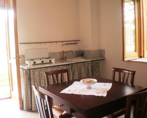 kuchnia z drewnianym stołem z krzesłami i kuchenką w obiekcie La Gabbianella e il Gatto w mieście Castellabate