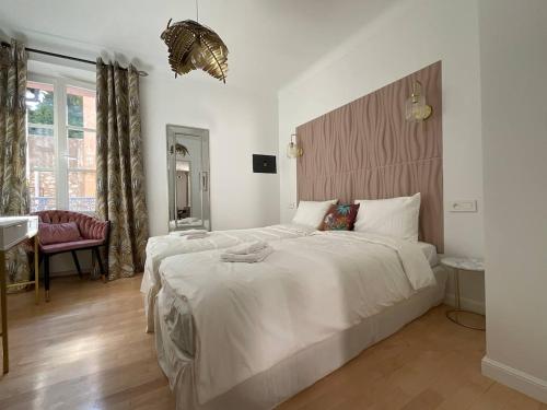 - une chambre avec un grand lit blanc et une tête de lit en bois dans l'établissement Newly renovated 3-rooms apartment in the heart of old Cannes, up to 6 persons, à Cannes