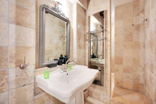 une salle de bain avec un lavabo blanc et un miroir dans l'établissement Appartement Maître Albert, à Paris