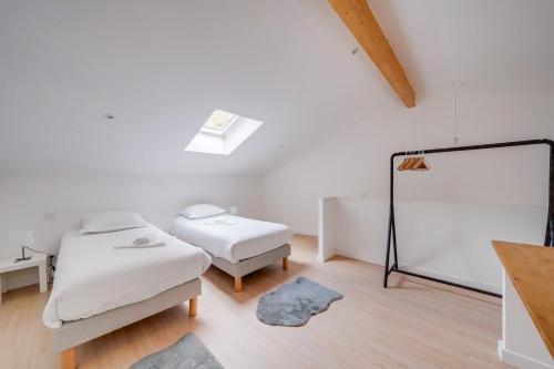Cette chambre blanche comprend 2 lits et un miroir. dans l'établissement Bel appartement confortable Bordeaux, à Bordeaux