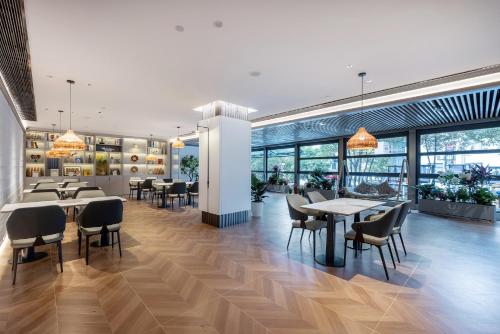 a restaurant with tables and chairs and windows at Lijiang OKDAY HOTEL in Lijiang