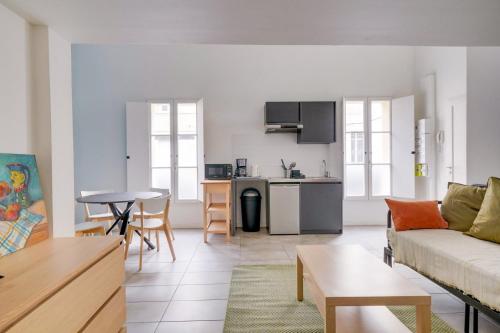 un salon avec un canapé et une table et une cuisine dans l'établissement Bel appartement confortable Bordeaux, à Bordeaux