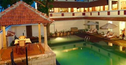 una gran piscina con sillas y una casa en Chidambara Vilas - A Luxury Heritage Resort en Kānādukāttān