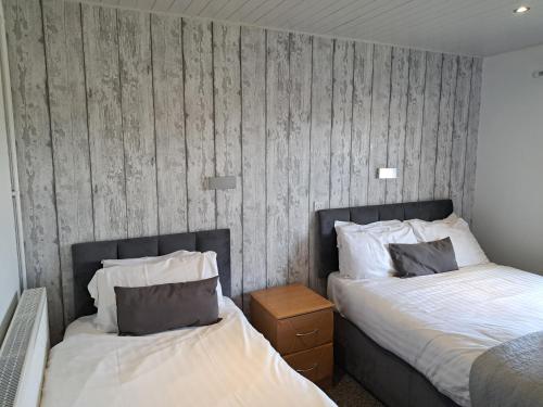 a bedroom with two beds and a wooden wall at Conwy Valley Hotel in Conwy