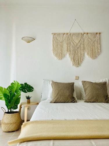 una camera da letto con un letto con lenzuola bianche e una pianta di Casa Sydney a Lagos