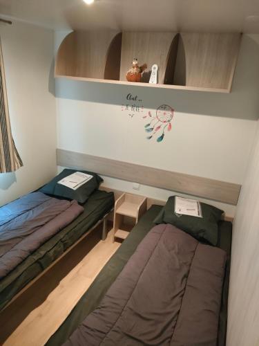 Cette petite chambre comprend 2 lits et une étagère. dans l'établissement L'orée du bois, à La Boissière-de-Montaigu