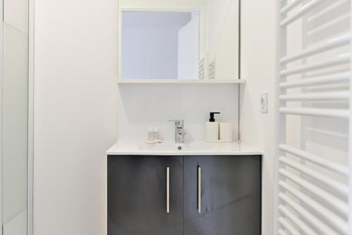une salle de bain avec un lavabo et un miroir dans l'établissement Spacieux 3 chambres avec balcon, à Colombes