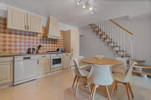 a kitchen with a wooden table and white chairs at Domaine des Oliviers - Les Borrels in Hyères
