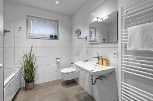 a white bathroom with a sink and a toilet at Ocean Star- 1 OG, Balkon, Hafenblick, Kamin in Olpenitz