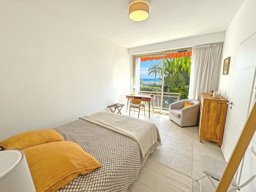 une chambre avec un lit, une table et une fenêtre dans l'établissement Cosy Sea Front Garden Nice, à Nice