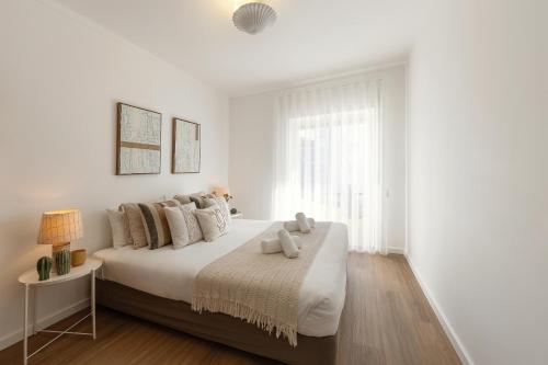 a white bedroom with a bed with two teddy bears on it at SeaBreeze Residence in Atouguia da Baleia