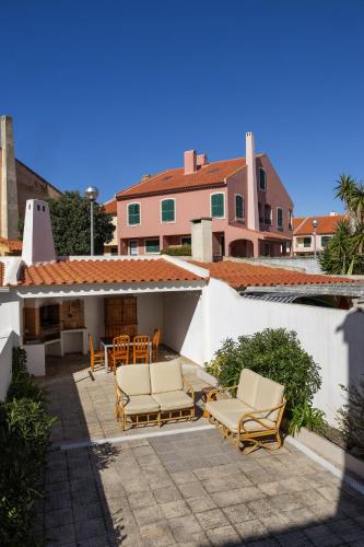 a patio with chairs and a table and a house at SeaBreeze Residence in Atouguia da Baleia