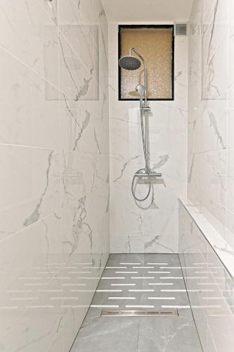 La salle de bains est pourvue d'une douche et de murs en marbre blanc. dans l'établissement Duplex agréable et comfortable dans le 9ème, à Paris