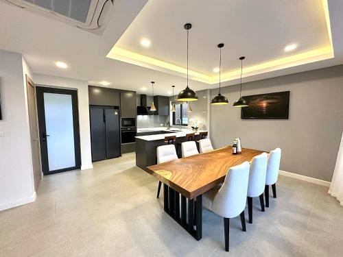 a kitchen and dining room with a wooden table and chairs at Zensiri Brand New Luxury Pool Villa in Pattaya