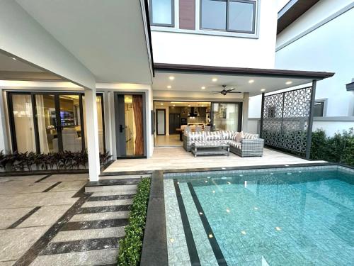 a house with a swimming pool in front of a house at Zensiri Brand New Luxury Pool Villa in Pattaya