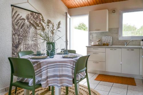 einen Esstisch mit grünen Stühlen und eine Küche in der Unterkunft jolie maison de vacances proche du lac de tanchet 6 personnes in La Pironnière