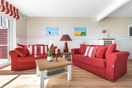 a living room with two red couches and a table at Hafenliebe- Sauna, Steg, Hafenblick, Kamin, Terrasse in Olpenitz