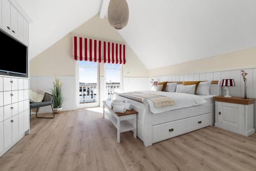 a white bedroom with a large bed and a television at Hafenliebe- Sauna, Steg, Hafenblick, Kamin, Terrasse in Olpenitz