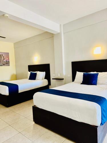 Un dormitorio con dos camas con sábanas azules y blancas. en Hotel Jazuli, en San José del Cabo