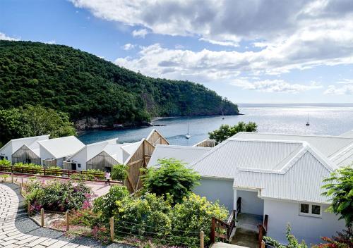 une vue aérienne d'une rangée de maisons près de l'eau dans l'établissement LES GALETS ROUGES LODGES & SPA, à Bouillante