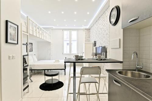 - une cuisine avec un évier et une table avec des tabourets dans l'établissement Studio Cosy Proche de Montmartre Charme du 18e, à Paris