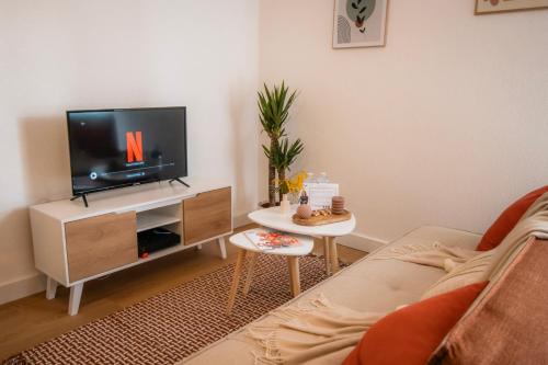 un salon avec un canapé et une télévision dans l'établissement Le cosy Mémorial - Parking - BY PRIMO CONClERGERIE, à Caen