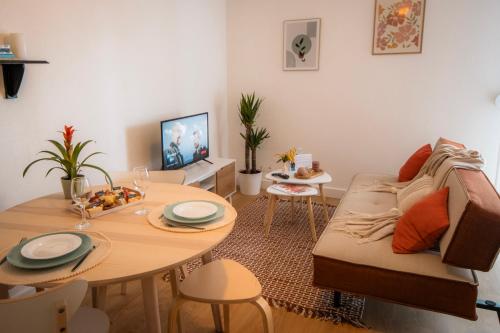 un salon avec une table et un canapé dans l'établissement Le cosy Mémorial - Parking - BY PRIMO CONClERGERIE, à Caen