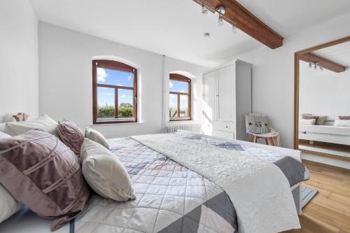 a white bedroom with a large bed and two windows at Landhaus Hohe Luft in Steinberg