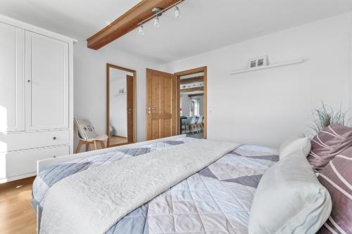 a white bedroom with a bed and a chair at Landhaus Hohe Luft in Steinberg