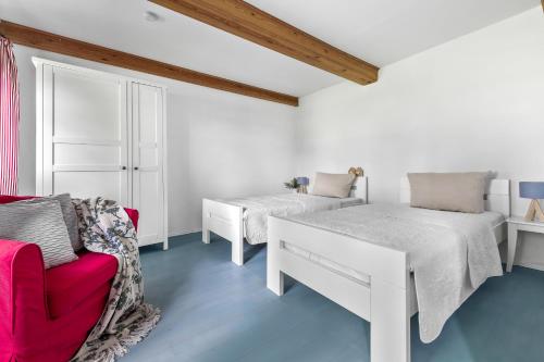 a white room with two beds and a red chair at Landhaus Hohe Luft in Steinberg