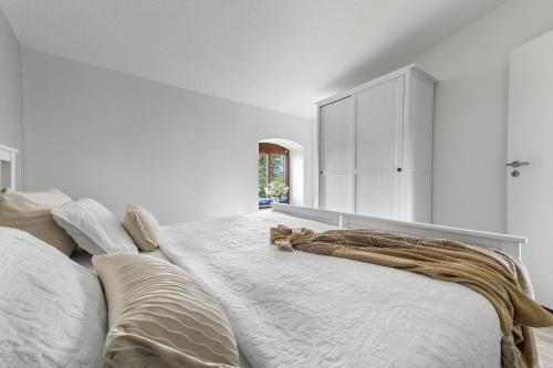 a white bedroom with a large bed with a blanket on it at Landhaus Hohe Luft in Steinberg