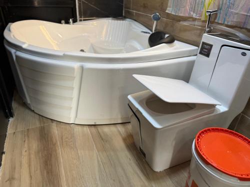 a bathroom with a white tub and a toilet at Studio avec Jacuzzi Aeroport AIBD in Déni Diarke