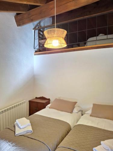 two beds in a room with a chandelier at Cal Tonico Rural in Ribes de Freser
