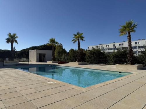 une piscine avec des palmiers et un bâtiment dans l'établissement T3 L'Eden- piscine- clim- commerces, au Lavandou