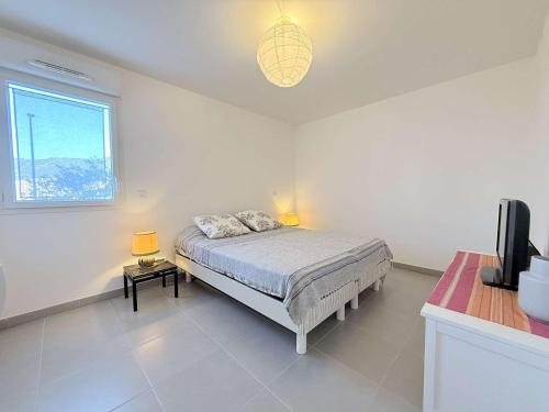 une chambre blanche avec un lit et une fenêtre dans l'établissement T3 L'Eden- piscine- clim- commerces, au Lavandou