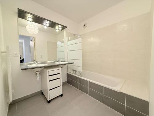 une salle de bain avec un lavabo et une baignoire et un lavabo dans l'établissement T3 L'Eden- piscine- clim- commerces, au Lavandou