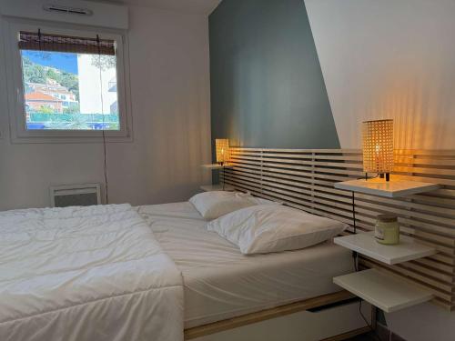 - une chambre avec un grand lit blanc et 2 tables de chevet dans l'établissement T2 centre ville/Plage/Commerces/Clim, au Lavandou