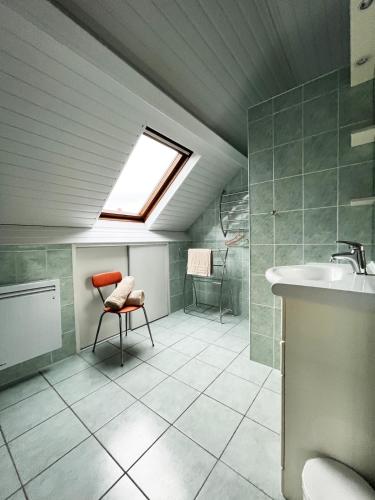 La salle de bains est pourvue d'une lucarne, d'une chaise et d'un lavabo. dans l'établissement L'Escale - Family home, à Granville