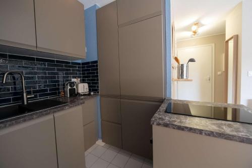 une cuisine avec un évier et un réfrigérateur dans l'établissement T2 cabine rénové/Piscine/Clim/commerces, au Lavandou