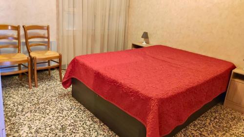 - une chambre avec un lit rouge et deux chaises dans l'établissement T2- Piscine- Commerces- Plages- Clim, au Lavandou