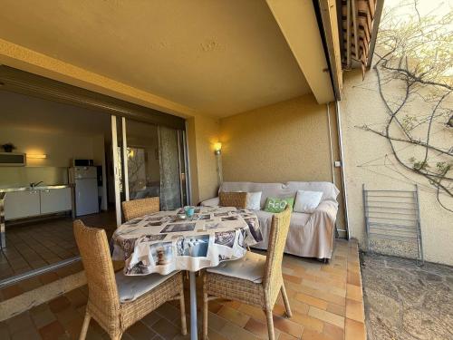 une table et des chaises sur une terrasse avec un canapé dans l'établissement T2 en rez de jardin , proche plage de St Clair et commerces, au Lavandou