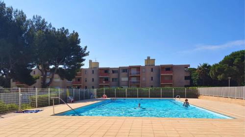 - une piscine avec des personnes devant un bâtiment dans l'établissement T2- Parking- Plages- Commerces, à Bormes-les-Mimosas