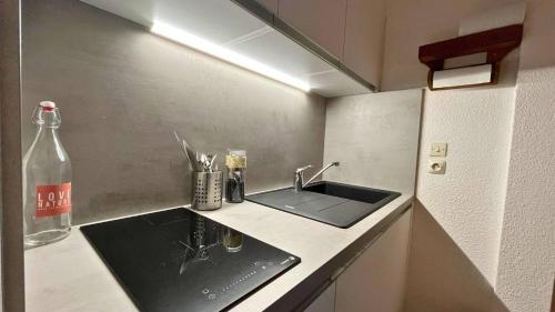 une cuisine avec un évier et une bouteille sur un comptoir dans l'établissement T2- Parking- Plages- Commerces, à Bormes-les-Mimosas