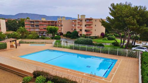 une grande piscine sur un patio à côté de quelques bâtiments dans l'établissement Studio- Piscine- Clim- Plages, à Bormes-les-Mimosas