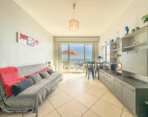 un salon avec un canapé et une vue sur l'océan dans l'établissement T2 pied dans l'eau- Vue mer- Proche commerces, au Lavandou