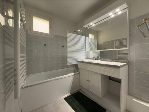 une salle de bain avec une baignoire, un lavabo et un miroir dans l'établissement T3 spacieux - climatisé - commerces - plages, au Lavandou
